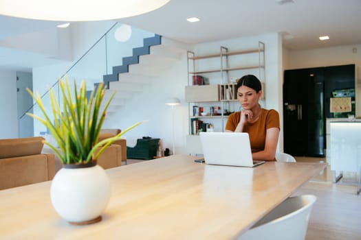 Woman sitting in living room using laptop looking at cam talk by video call with business friend relatives, head shot. Job interview answering questions