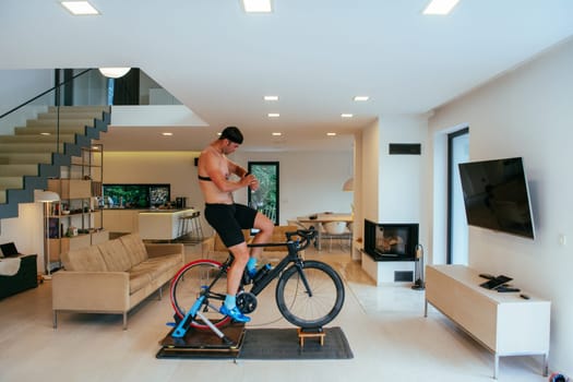 A triathlete riding a triathlon bike on a machine simulation in a modern living room.