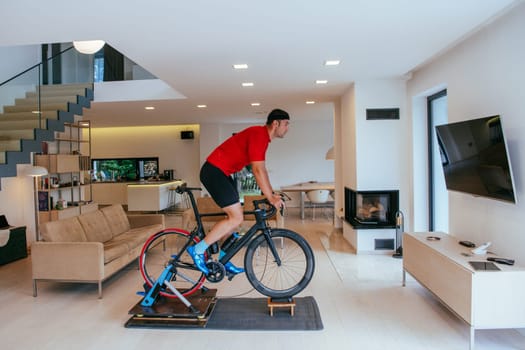 A triathlete riding a triathlon bike on a machine simulation in a modern living room.
