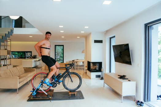 A triathlete riding a triathlon bike on a machine simulation in a modern living room.