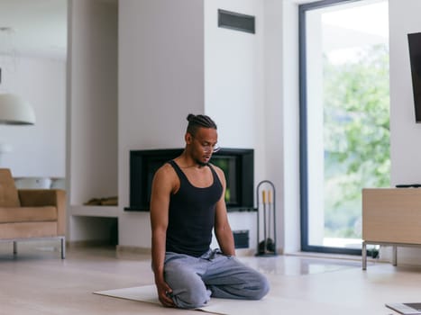 Training At Home. Sporty man doing the training while watching an online tutorial on a laptop, exercising in the living room, free space
