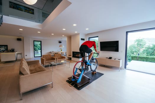 A triathlete riding a triathlon bike on a machine simulation in a modern living room.