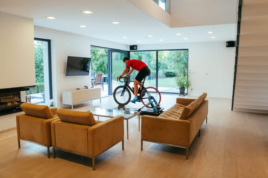 A triathlete riding a triathlon bike on a machine simulation in a modern living room.