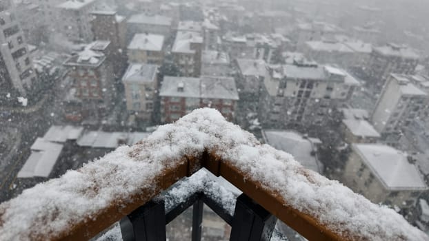 Snowfall blankets buildings in a city during a cold winter day.