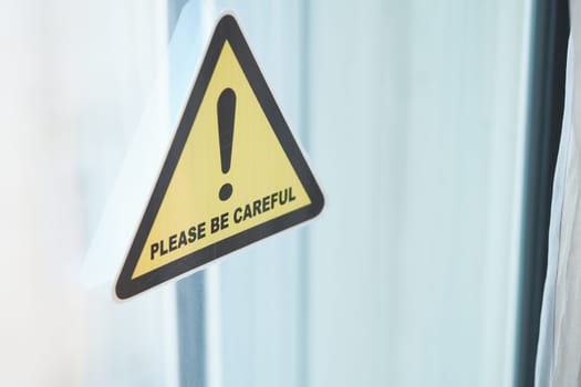 Warning notice displayed on a window asking for caution indoors.