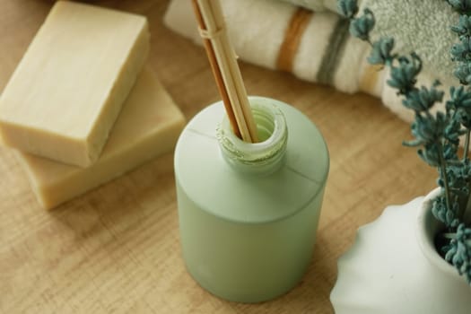 A green bottle holds bamboo sticks beside natural soap and towels.