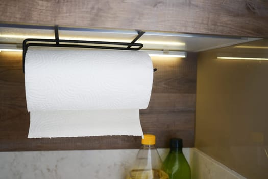 A roll of paper towels hangs on a kitchen holder during cooking activities.