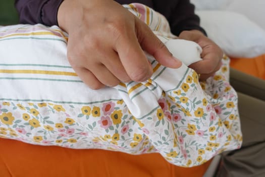 A person adjusts a pillowcase with flower patterns while seated comfortably.