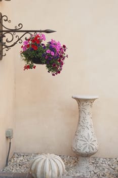 Colorful blooms adorn a hanging basket near a decorative stone fountain.