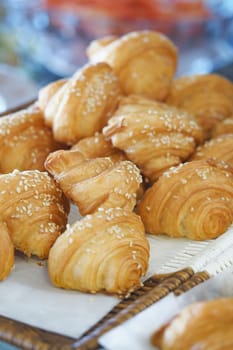 Flaky croissants topped with sesame seeds are arranged on a platter.