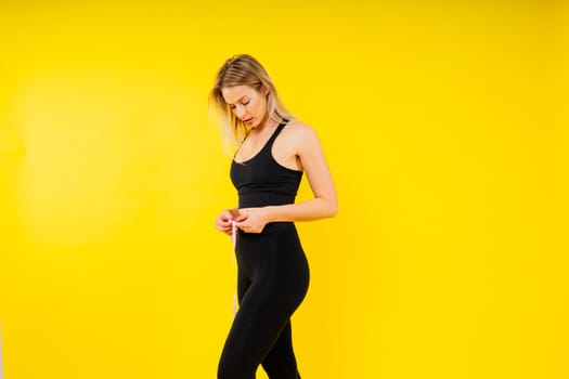 Smiling slim woman measuring her waist with tape. Fit young lady perfect shape, happy her body