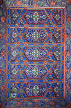 background of painted carved wooden celling with traditional Uzbek ornaments and colorful oriental patterns in Tashkent in Uzbekistan