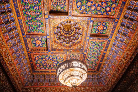 beautiful carved wooden painted ceiling with chandelier in Museum of Art of Uzbekistan with traditional Uzbek ornaments and colorful oriental patterns in Uzbekistan