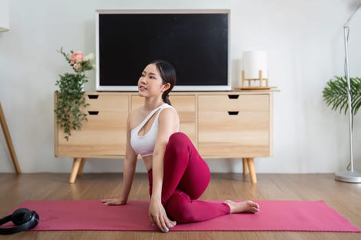 A passionate yogi engages in a twisting pose, focusing on flexibility and strength while enjoying the serenity of her home during practice.