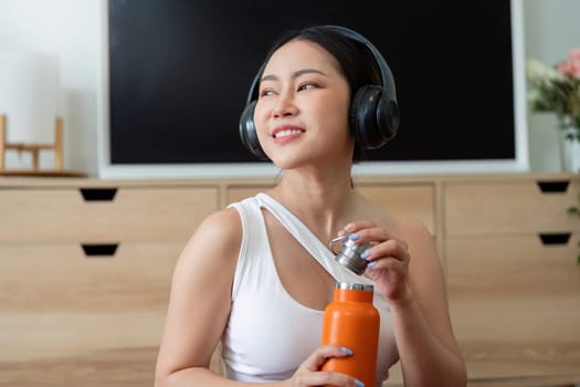 With a cheerfully focused expression, a fitness lover prepares to enjoy water from her bright orange bottle, enhancing her hydration strategy.