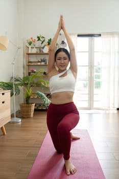 This image captures a woman in a yoga pose with arms extended upward, highlighting her commitment to mindfulness and physical fitness in a peaceful setting.
