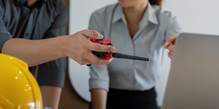 A moment of collaboration as one engineer hands a communication device to another. This interaction emphasizes the necessity of clear communication in engineering processes.