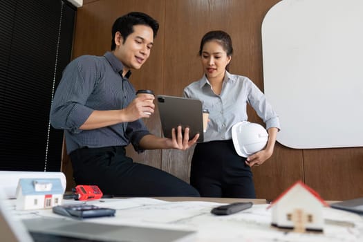 Engineers discuss insights and project details on a tablet, illustrating the fusion of technology and collaboration in modern workplaces.