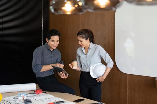 Two engineers brainstorm innovative solutions while sharing drinks, demonstrating teamwork and forward-thinking in their workspace.