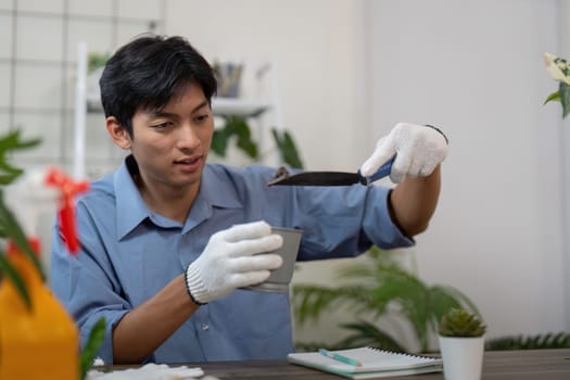 Focused on reshaping his plant's environment, this man utilizes a trowel to enhance growth conditions during a repotting session.