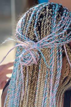 A unique braided hairstyle combines shades of pink, blue, and blonde with artistic precision. The vibrant look highlights creativity and offers a modern take on traditional braiding techniques.