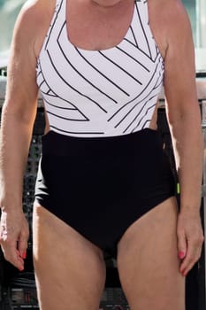 A stylish woman is seen wearing a minimalist one-piece swimsuit. Her poised presence, coupled with the contrast of modern design and vibrant colors, exudes confidence and a relaxed summer aesthetic.