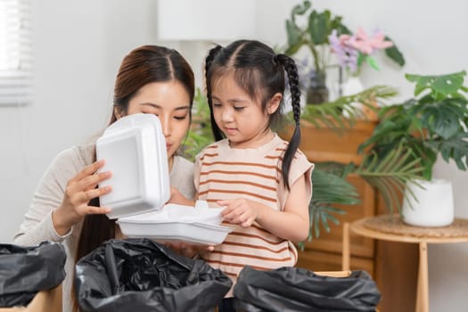 A mother shows her daughter how to reuse takeaway containers, instilling eco-friendly values through fun and creative play at home.