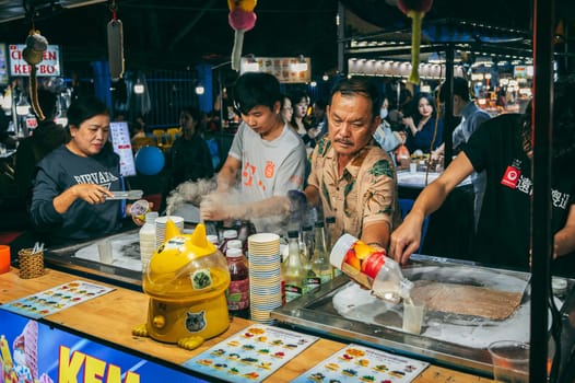 Vietnamese chefs and vendors make ice cream at a asian Night market of street food stand in Da Nang in Asia. Da Nang, Vietnam - November 30, 2024