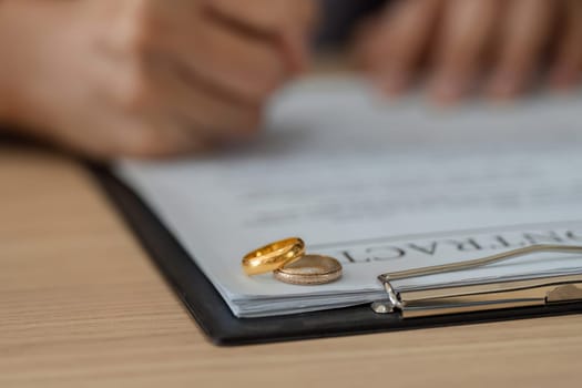 Two wedding rings rest on a legal document, indicating a divorce agreement, symbolizing the end of a significant relationship.