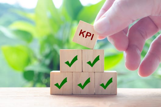Hand holding wooden cube with text KPI. Key Performance Indicator concept