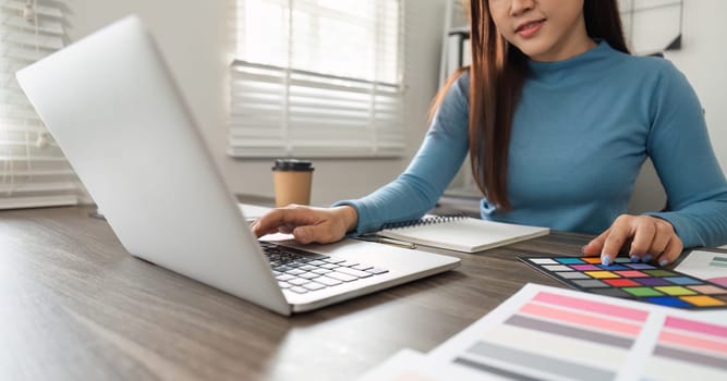 A creative professional thoughtfully examines vibrant color swatches, balancing digital design and tactile inspiration in an efficient workspace.