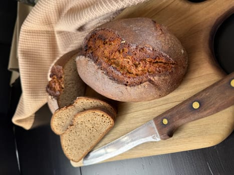 Fresh sliced Sourdough Bread on wooden cutting board isolated on white background, top view. Yeast rye or wheat artisan bread and knife.