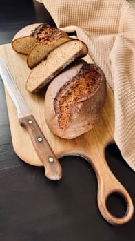 Fresh sliced Sourdough Bread on wooden cutting board isolated on white background, top view. Yeast rye or wheat artisan bread and knife.