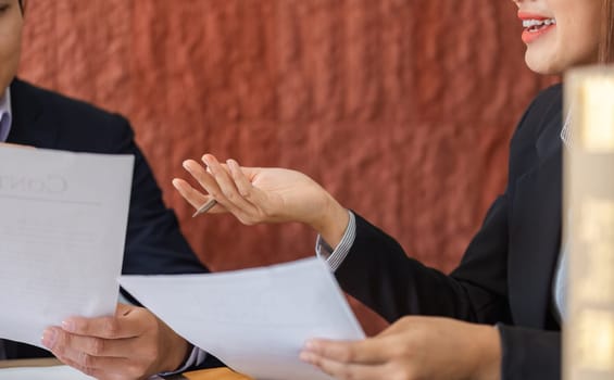 A lawyer reviews legal papers with a client, engaging in a detailed conversation about the implications and significance of the documents presented.