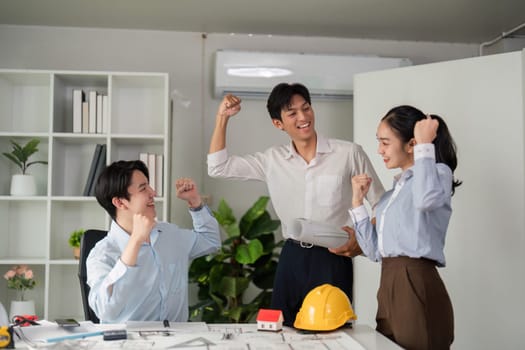 A team of three professionals shares an exciting moment of collaboration while discussing project plans, showcasing enthusiasm in their workspace.