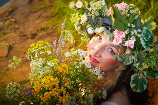 Slavic plump chubby girl in long white dress on the feast of Ivan Kupala with flowers and water in a river or lake on summer evening