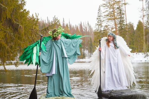 Girls in elegant white and green dresses pose on the lake, embodying the magical transition between winter and spring during a role-playing shoot.