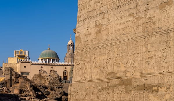 Excavations and modern buildings around the well-preserved facade of the Temple of Esna with carvings