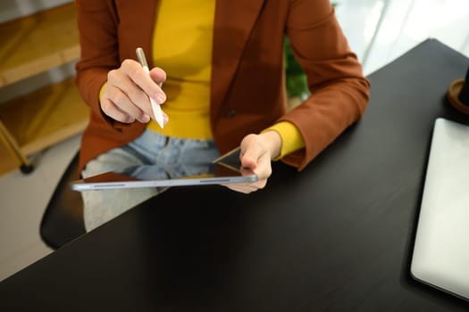 Close up shot of young creative woman working with digital tablet at office desk.