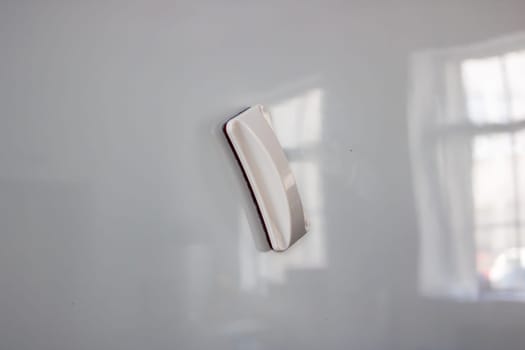 A white board eraser is currently positioned on top of a clean and smooth white board, ready to be used for erasing marks