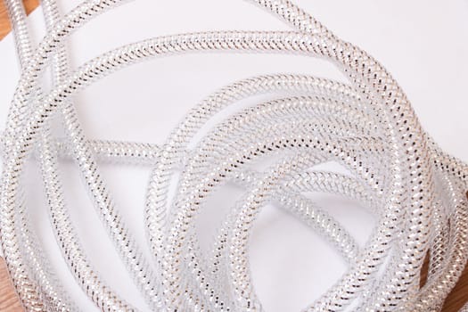 This is a detailed closeup image showcasing a beautiful silver chain elegantly lying on a clean white surface, highlighting its shine and texture