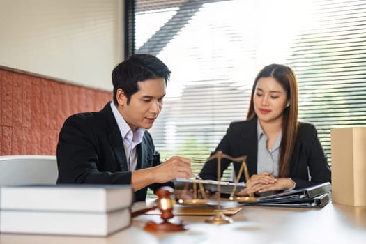 A male lawyer engages with a female client, discussing legal documents and strategies in a professional office environment, emphasizing collaboration and expertise.
