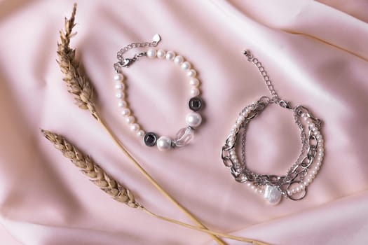 Jewelry on satin fabric with pearl bracelets and wheat elements. Handmade bijouterie And natural aesthetics in fashion.