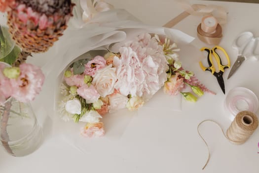 Beautiful floral bouquet wrapped in elegant paper, surrounded by tools and ribbons, ready for gifting or special occasion. flower shop