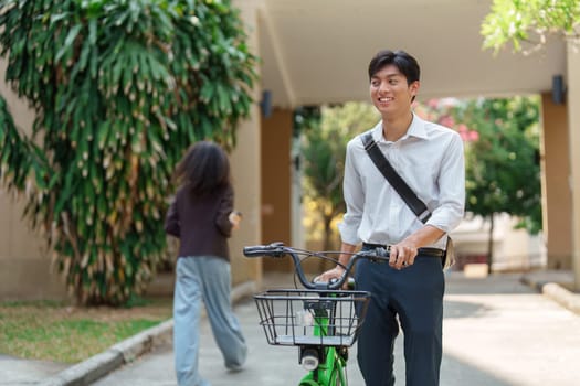 A young professional enjoys a breezy day while walking with his bicycle, reflecting a commitment to sustainable transportation and healthy living.