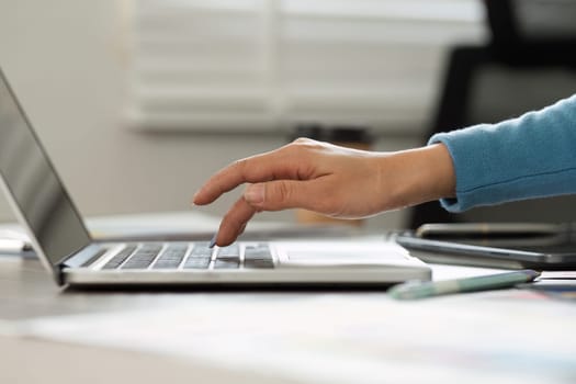 An individual engages intently with their laptop keyboard, enhancing their creative workflow while managing design tasks in a modern setting.