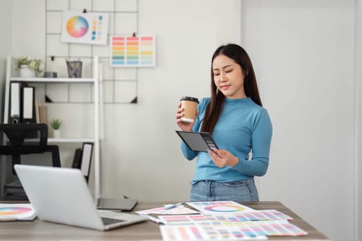 A thoughtful designer reviews design samples on her tablet, blending digital insights with her coffee break in a creative environment.