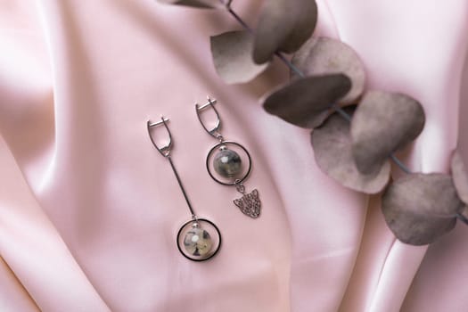 Female Jewelry. Vintage bijouterie jewelry. Beautiful handmade silver earrings on pink silk background. Flat lay, top view copy space and empty space for text.