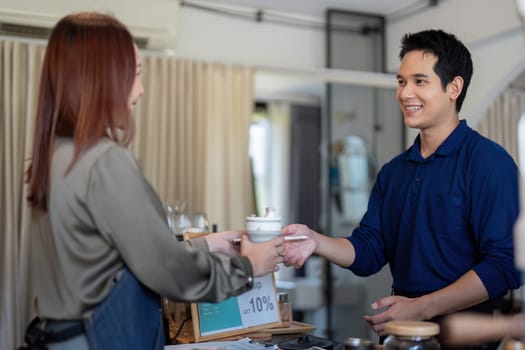 A cheerful barista serves a beverage to a customer, highlighting the importance of sustainable practices through ecologically conscious choices.