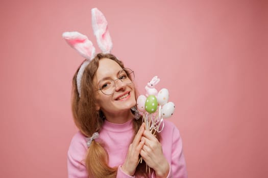 Happy woman in bunny ears holding a bouquet of colorful Easter eggs, smiling playfully. Festive spring mood, holiday joy, and seasonal celebration